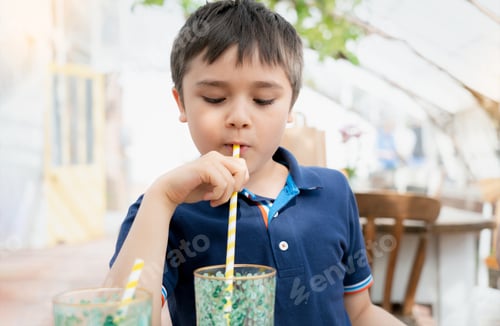 Preview: Kid drinking fresh juice for breakfast in cafe, Happy child boy drinking glass of soda or soft cold