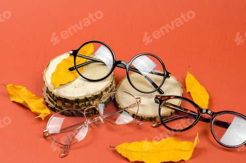 Preview: Eyeglasses on a wooden podium with yellow autumn leaves. Autumn sale of eyeglasses
