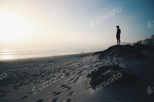 Preview: Man standing on a beach with foot prints in the sand