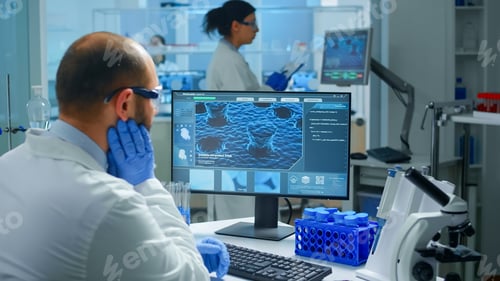 Preview: Worried chemist doctor working on pc examining vaccine evolution