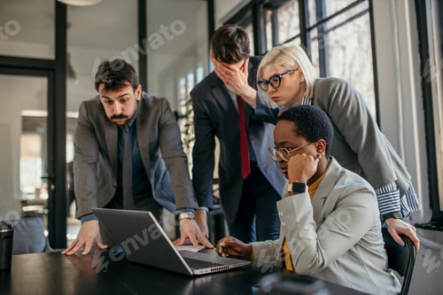 Preview: Business people reading shocking news on laptop in office meeting