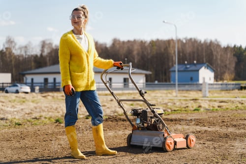 Preview: Woman villager is using aerator machine to scarification and aeration of lawn or meadow
