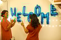 Preview: Enthusiastic People Celebrating with Blue Balloon Decorations Indoors