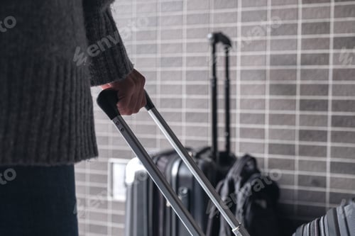 Preview: Closeup image of a woman holding and dragging a black baggage for traveling in the outdoors