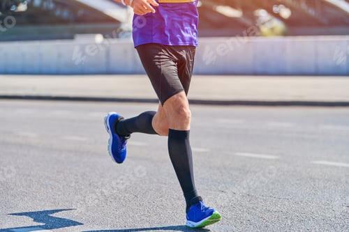 Preview: Athletic man jogging in sportswear on city road