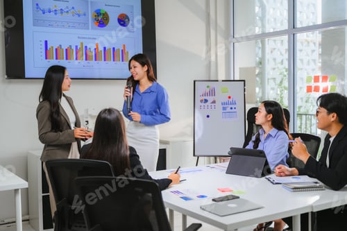 Preview: Asian businesswomen speaking into microphone during presentation in meeting room