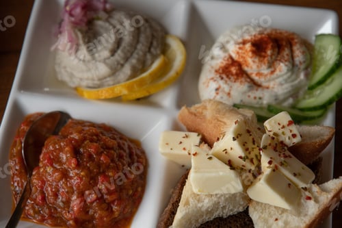 Preview: Closeup butter pieces atop bread toasts on plate with meze set of assorted pate and appetizers