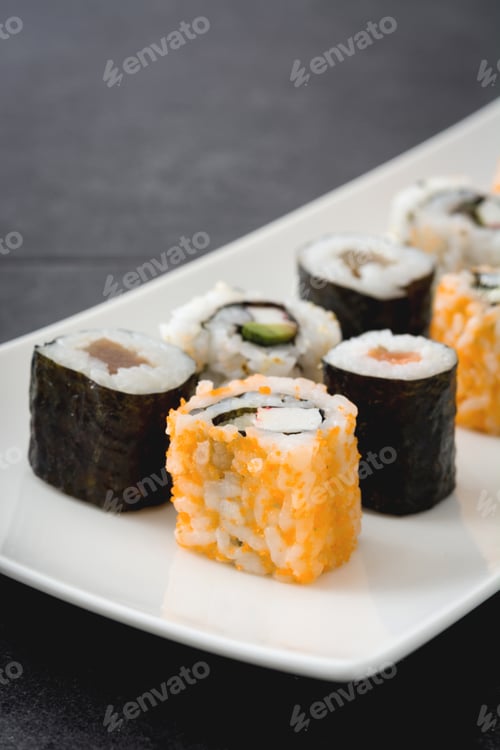 Preview: Delicious sushi rolls sitting on a white plate on a dark grey surface