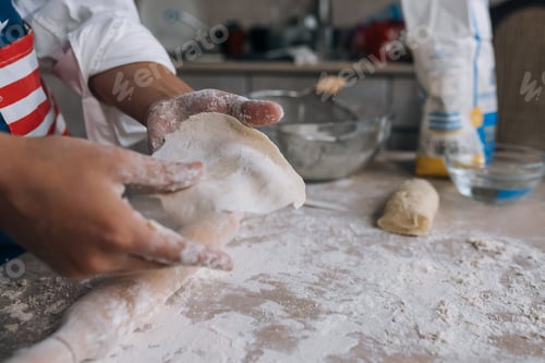 Preview: Young housewife in an apron kneads dough with her hands.