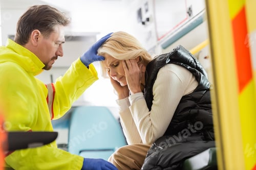 Preview: Paramedic in latex gloves touching head of middle aged woman in emergency car