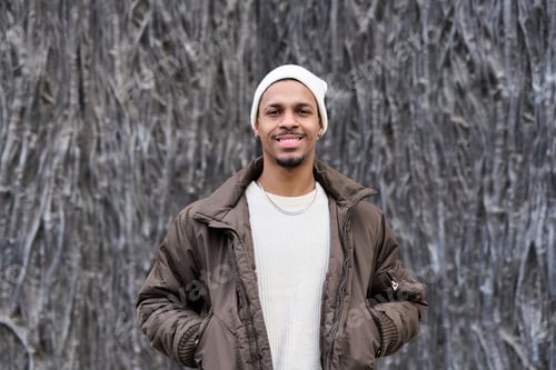 Preview: Young man smiling and posing with hands in pockets wearing winter clothes