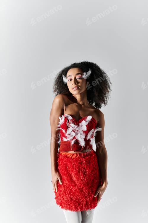 Preview: Young woman sports a bold red feathered outfit against a grey backdrop