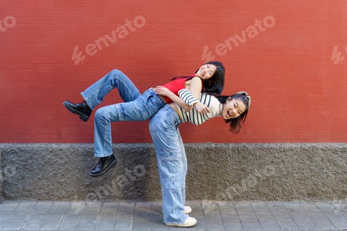 Preview: Happy Asian woman lifting friend on back