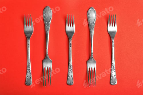 Preview: Vintage silver forks on red background, flat lay