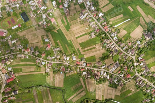 Preview: Top down aerial view of town or village with rows of buildings and curvy streets between green