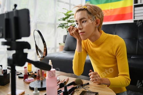 Preview: Young queer man beauty make up artist or vlogger recording makeup tutorial in home studio.
