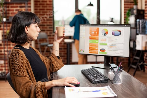 Preview: Woman analyzing data with coffee in hand