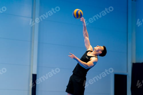 Preview: a young pumped-up guy sportsman during a volleyball game or match hits the ball