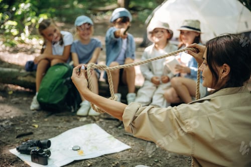 Preview: Sharing knowledge, how to tie the knot. Woman is doing tour for group of kids in the forest