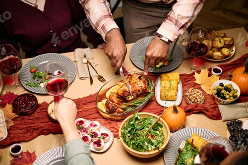 Preview: Hands of Diverse Guests Carving Roast Turkey during Thanksgiving Celebration