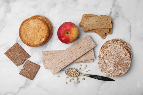Preview: Rye crispbreads, rice cakes and rusks on white marble table, flat lay