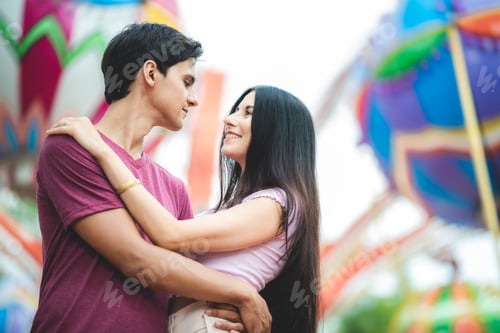 Preview: Positive young loving couple walking outdoors in amusement park, theme park