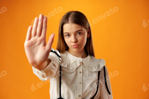 Preview: Teen girl extend hand in block gesture against yellow background