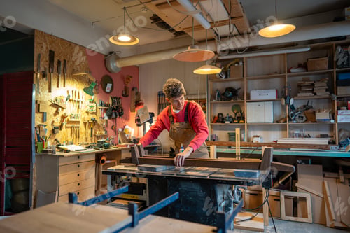 Preview: Concentrated man carefully working in carpentry creative studio, engaged in creation of bed.