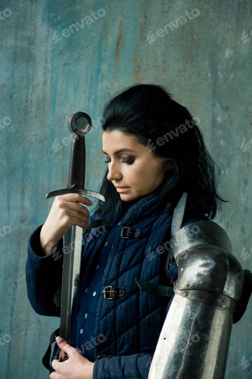 Preview: Beautiful brunette woman in ancient iron knightly armor. Medieval female knight in armor.