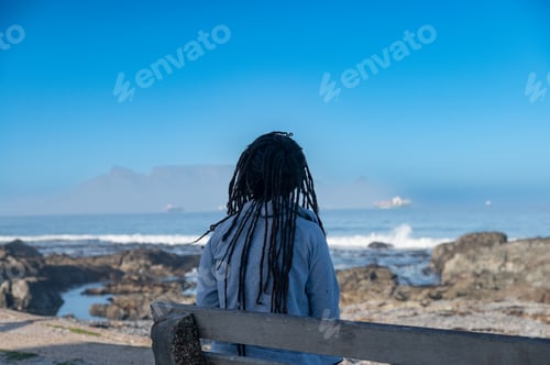 Preview: Woman seen sitting on bench and looking at table mountain