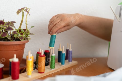 Preview: Unrecognizable Hand Picking Thread Spool from Sewing Table