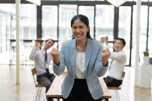Preview: Young Asian businesswoman celebrating success with her coworker in the office room.