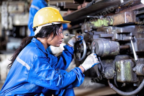 Preview: Woman in uniform working in machinery shop trouble shooting repair faulty mechanical rotating part