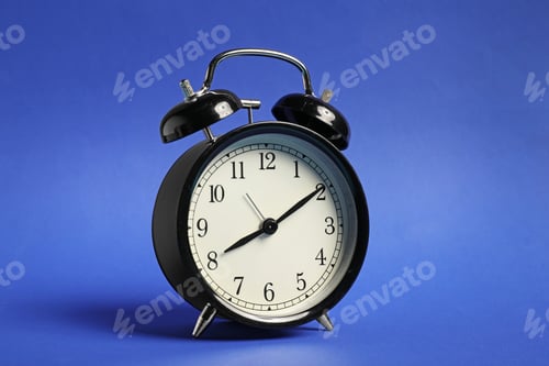 Black Alarm Clock Against A Blue Background