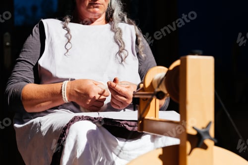 Preview: Unrecognizable senior woman spinning wool on machine on sunny day
