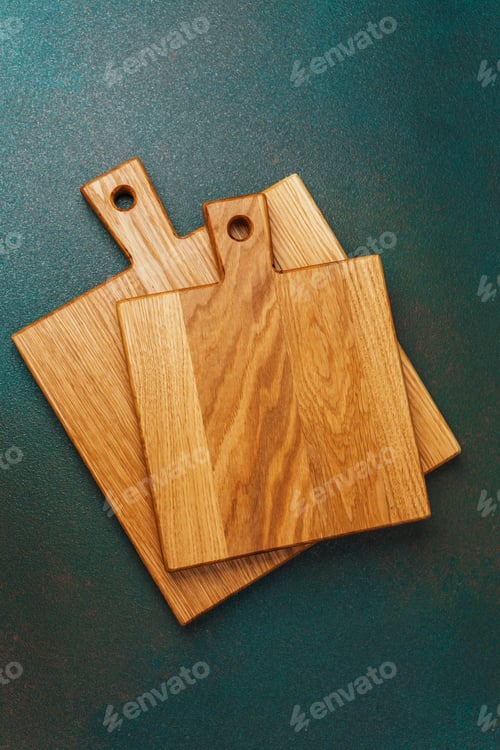 Preview: Cutting boards stacked on a green surface showcasing their natural wood texture