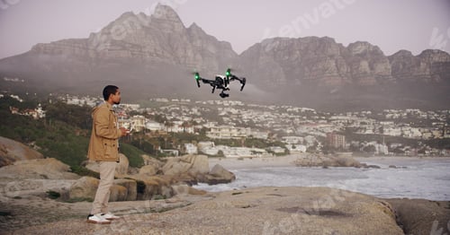 Preview: Soaring through the sky. Full length shot of a young man flying his drone outdoors.