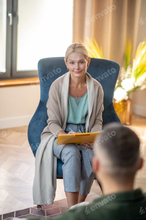 Preview: Beautiful psychologist sitting in armchair and helping patient