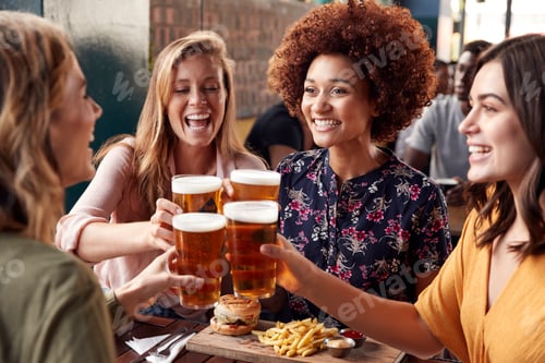 Preview: Four Young Female Friends Meeting For Drinks And Food Making A Toast In Restaurant