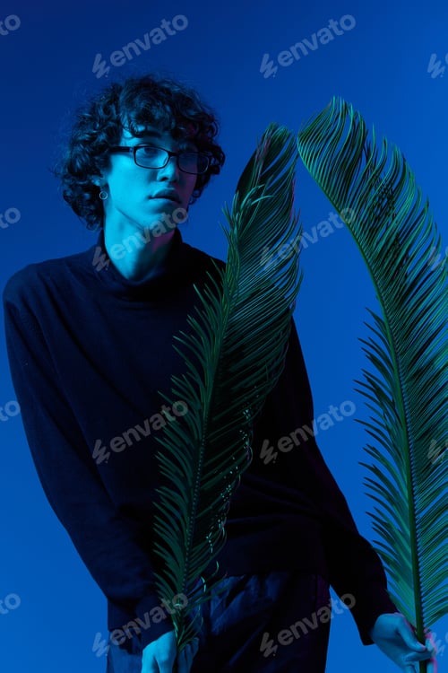 Preview: Man wearing glasses with palm leaves portrait, hipster lifestyle, portrait blue background, mixed