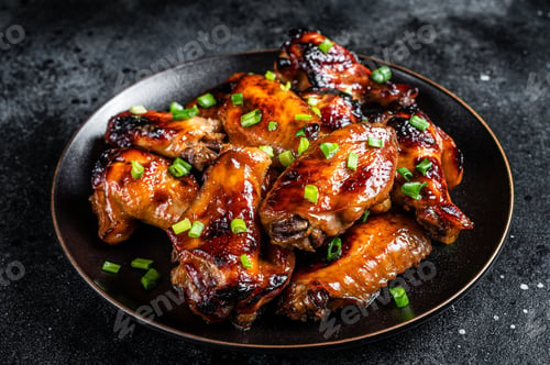 Preview: Baked chicken wings with sweet chili sauce in a plate. Black background. Top view