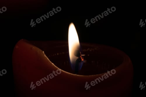 Preview: Closeup shot of the light of a burning candle on a black background