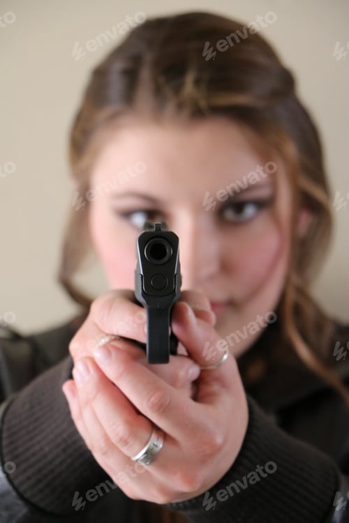 Preview: Vertical portrait of young woman pointing .9mm weapon.