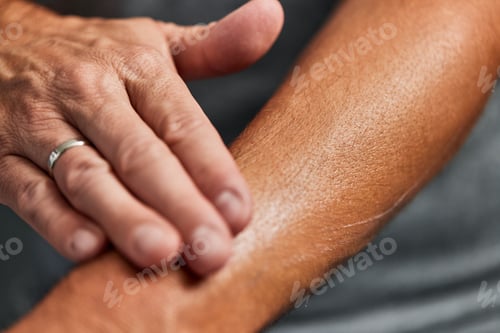 Preview: A man putting moisture on his dry skin, taking care of it, rubs into the skin with his fingers.
