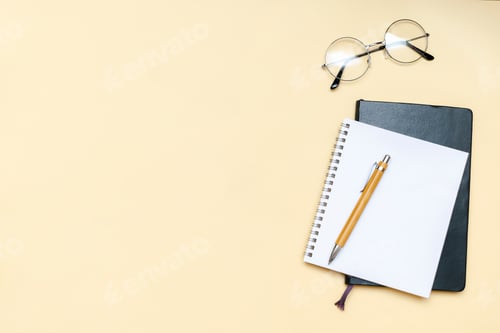 Preview: Black blank notebook, pen, glasses, goggles, alarm clock top view on beige background. Top view desk