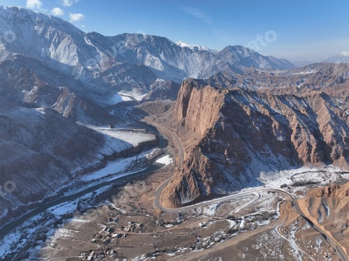 Preview: Aerial view of a winding road and river in a snowy mountain range