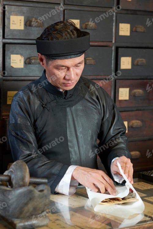 Preview: Drugstore worker wrapping dry shiitake mushrooms