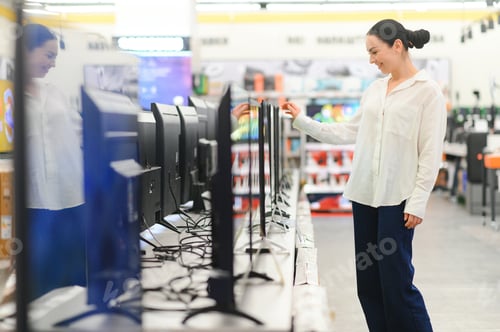 Preview: young woman chooses plasma in store of household appliances