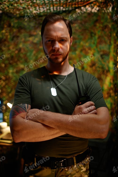 Preview: Young serious security officer crossing his arms by chest and looking at camera