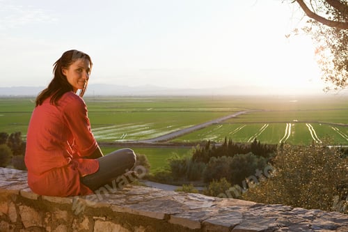 Preview: Woman enjoying a serene sunset over lush farmland.